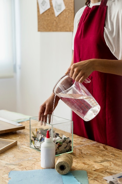 Mulher, despejar, água, em, recipiente vidro, com, torned, papel