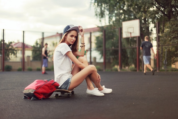 Foto grátis mulher desportiva ao ar livre sentado no skate