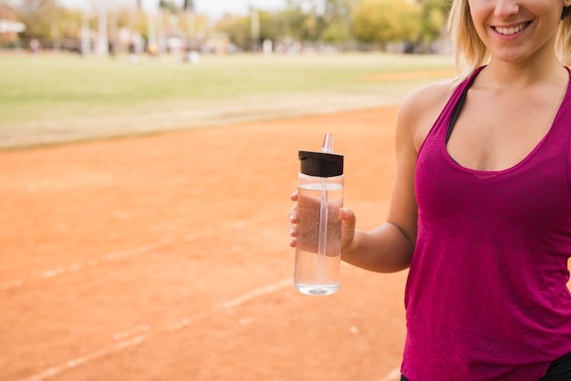 Mulher desportiva com garrafa de água na pista do estádio