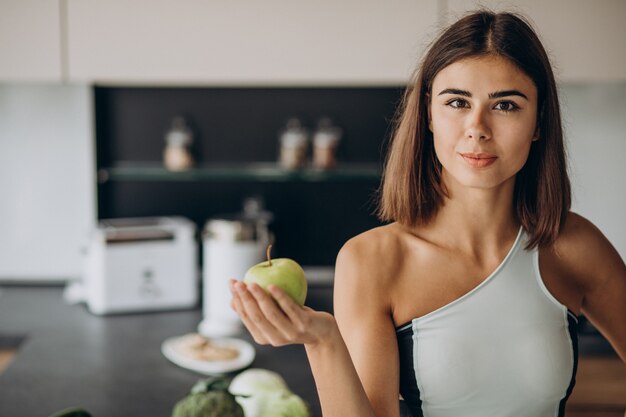 Mulher desportiva com maçã na cozinha