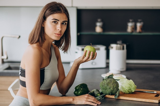 Mulher desportiva com maçã na cozinha