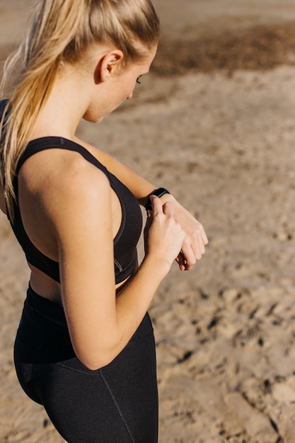 Mulher desportiva com smartwatch na praia