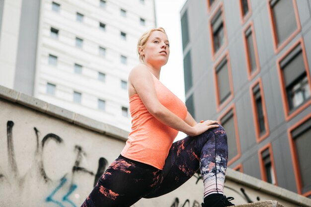 Mulher desportiva, estendendo-se em ambiente urbano