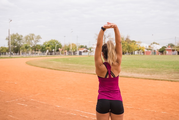 Mulher desportiva, estendendo-se na pista do estádio