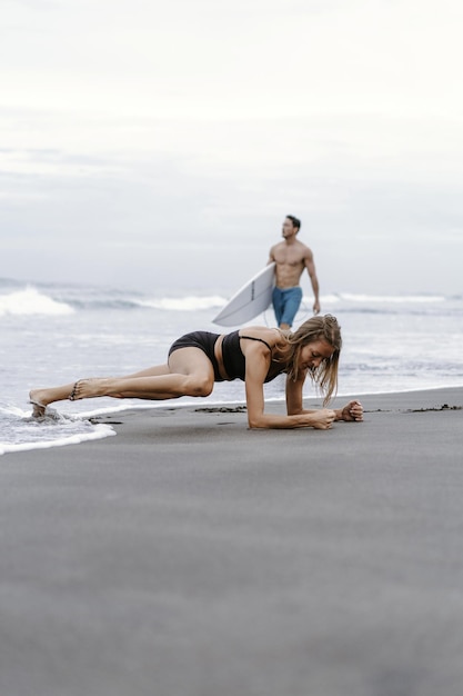 Mulher desportiva fazendo exercício de alpinista - corra na prancha para queimar gordura. Praia do sol, fundo do céu azul. Estilo de vida saudável no retiro de ioga da ilha tropical, atividade ao ar livre, férias de verão em família.