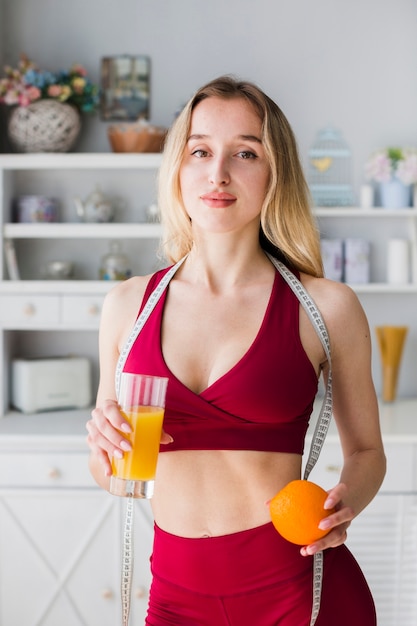 Mulher desportiva na cozinha com suco saudável