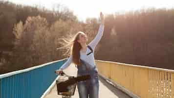 Foto grátis mulher despreocupada posando com bicicleta na ponte