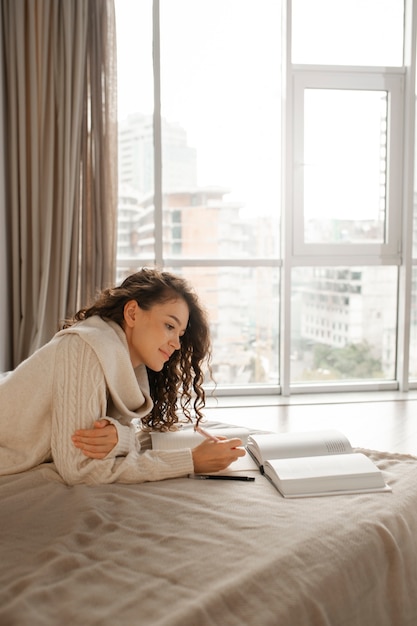 Foto grátis mulher digital desconectando em casa lendo livro na cama