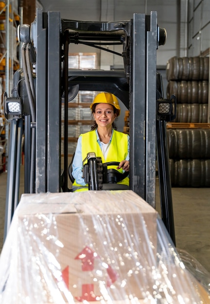 Foto grátis mulher dirigindo máquina de carregamento de armazém