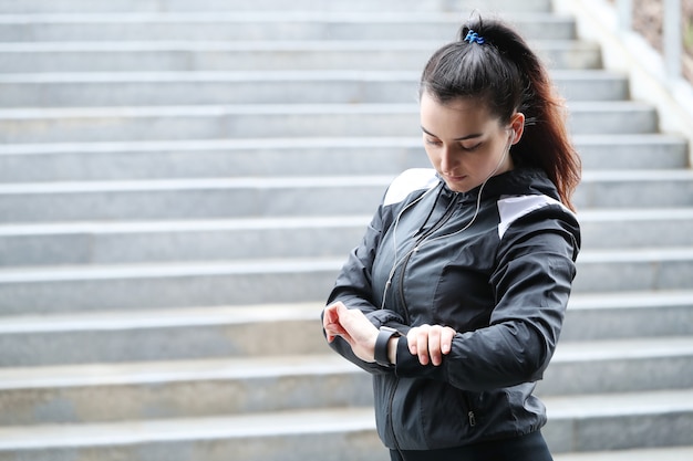 Mulher do esporte ao ar livre olhando seu relógio de pulso