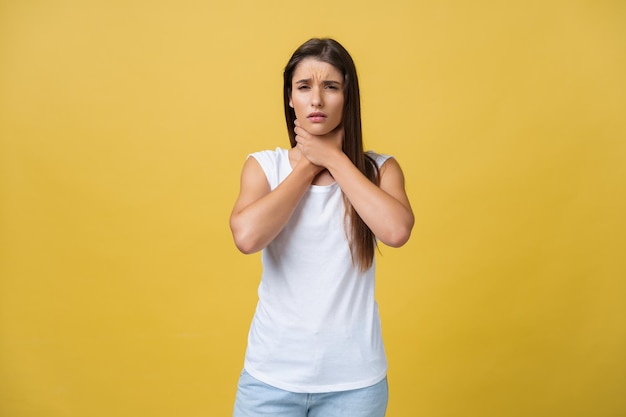 Mulher doente que sofre de dor de garganta isolada sobre fundo amarelo