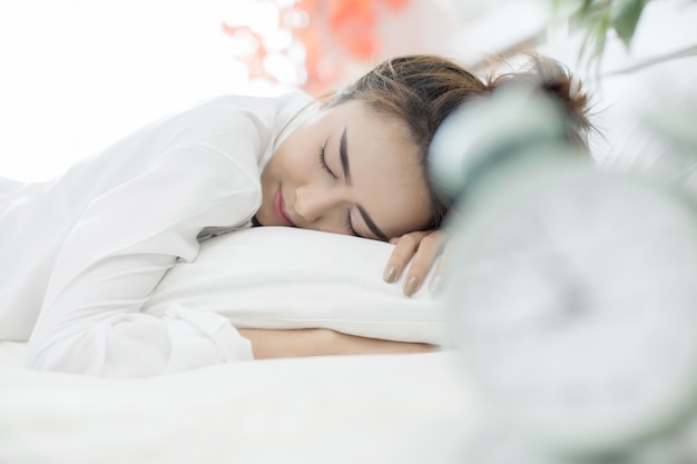 Mulher dormindo na cama enquanto seu alarme mostra a hora de início em casa no quarto