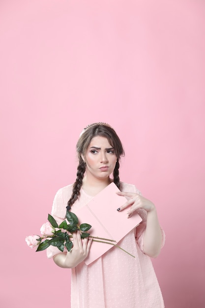 Foto grátis mulher duvidosa posando enquanto segura rosas e livro