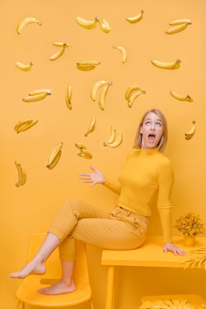 Foto grátis mulher e bananas flutuantes em uma cena amarela