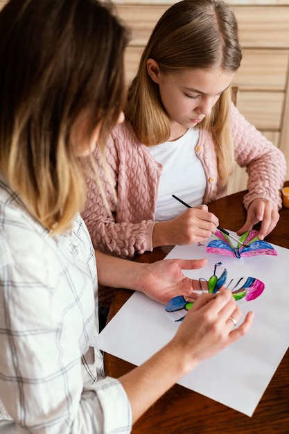 Mulher e criança em close pintando borboletas