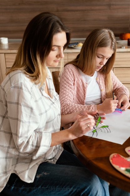 Mulher e criança em plano médio pintando borboletas