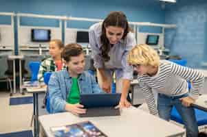 Foto grátis mulher e dois alunos olhando para tablet