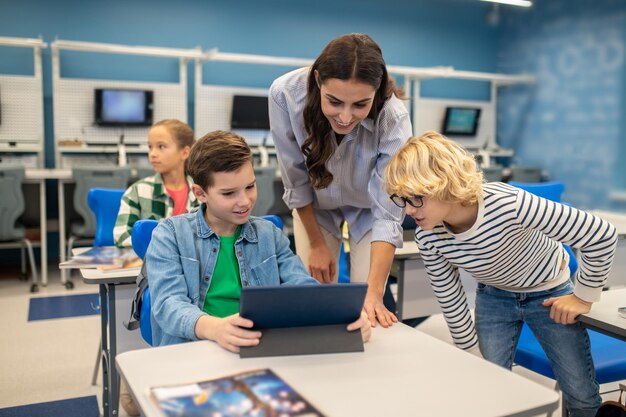 Mulher e dois alunos olhando para tablet