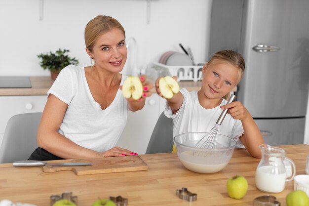 Mulher e garota de tiro médio segurando maçãs