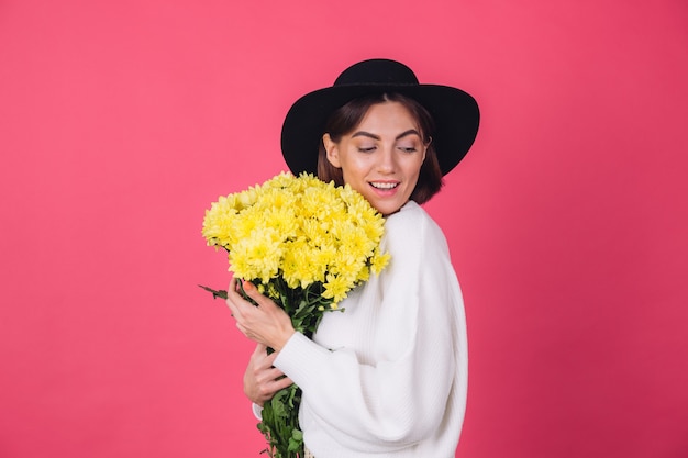 Mulher elegante com chapéu e suéter branco casual na parede vermelha