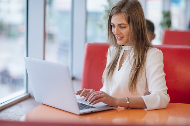 Mulher elegante com face de sorriso digitando em seu laptop