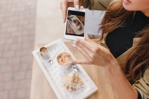 Foto grátis mulher elegante com manicure branca segurando o smartphone enquanto desfruta do almoço