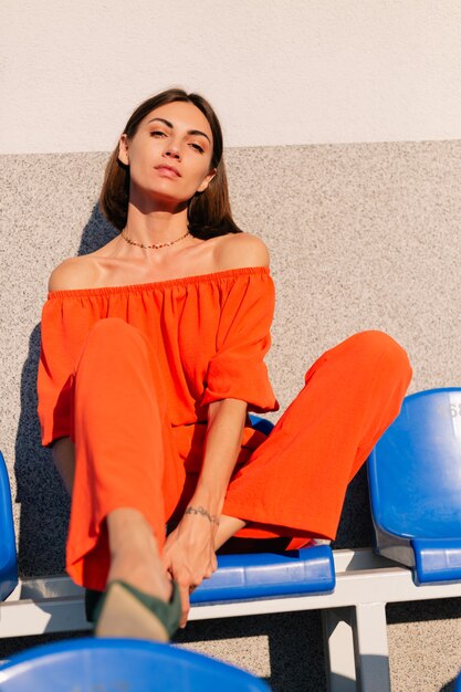 Mulher elegante com roupas laranja ao pôr do sol no estádio da ciclovia posando