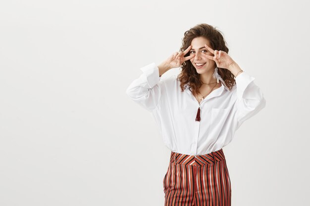 Mulher elegante e alegre mostrando o símbolo da paz e sorrindo