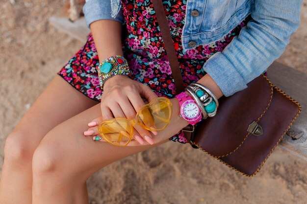 Mulher elegante em férias na praia com acessórios coloridos e joias de óculos de sol amarelo e bolsa