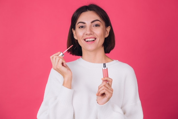 Mulher elegante em suéter branco casual na parede rosa vermelha