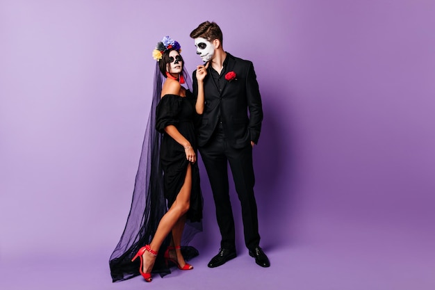 Foto grátis mulher elegante em traje de noiva morta curtindo sessão de fotos de halloween casal estiloso de zumbis esperando a festa