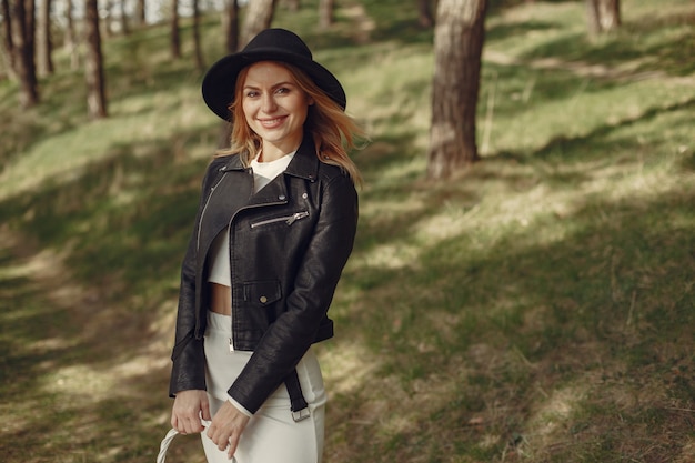 Mulher elegante em um chapéu preto em uma floresta de primavera