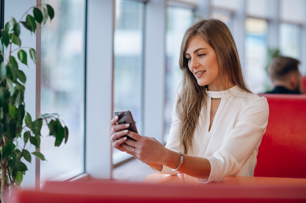 Mulher elegante em um restaurante que olha seu telefone móvel