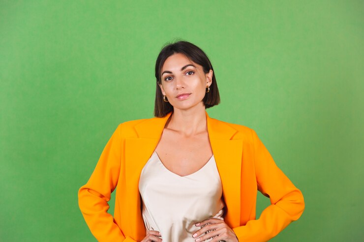 Foto grátis mulher elegante em um vestido bege de seda e um blazer laranja enorme em um sorriso verde, emoções positivas