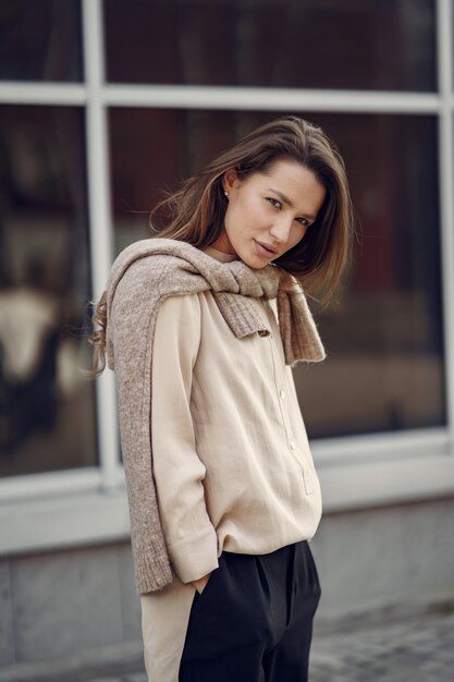 Mulher elegante em uma camisa marrom em uma cidade de primavera