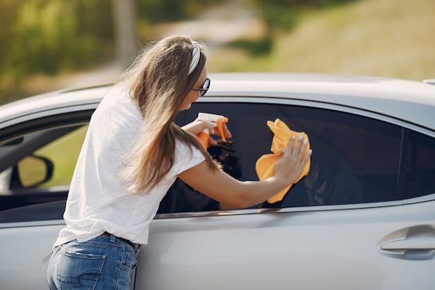 Mulher elegante limpa o carro com um pano