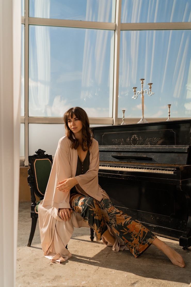 Foto grátis mulher elegante posando perto de piano em uma elegante sala de luz.