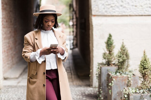 Mulher elegante sorridente, olhando para o telefone com espaço de cópia