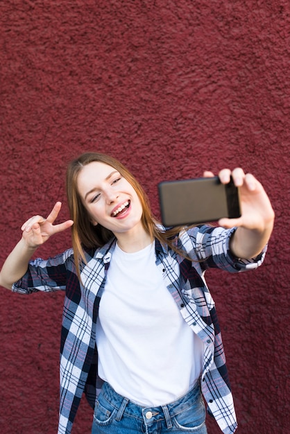 Mulher elegante, tendo selfie com gesto de sinal de paz