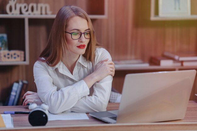 Mulher elegante trabalha em uma mesa de laptop em um escritório moderno