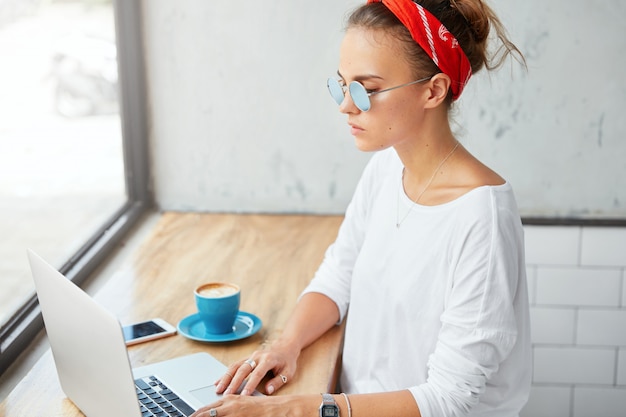 Mulher elegante usando bandana sentada em um café