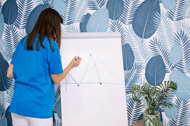 Foto grátis mulher, em, azul, t-shirt, desenho, gráfico, com, marcador, ligado, flipchart, contra, papel parede
