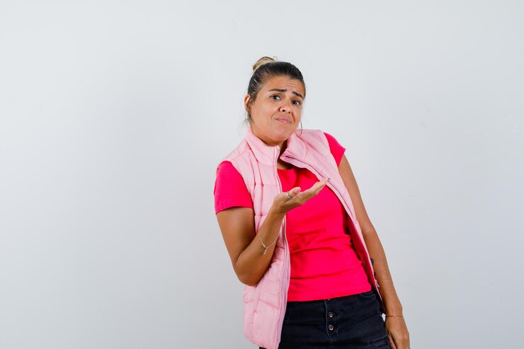 Foto grátis mulher em camiseta, colete mostrando algo de maneira questionadora e parecendo confusa