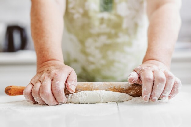 Mulher em casa amassando massa para cozinhar pão ou pizza. Conceito de comida caseira. Estilo de vida