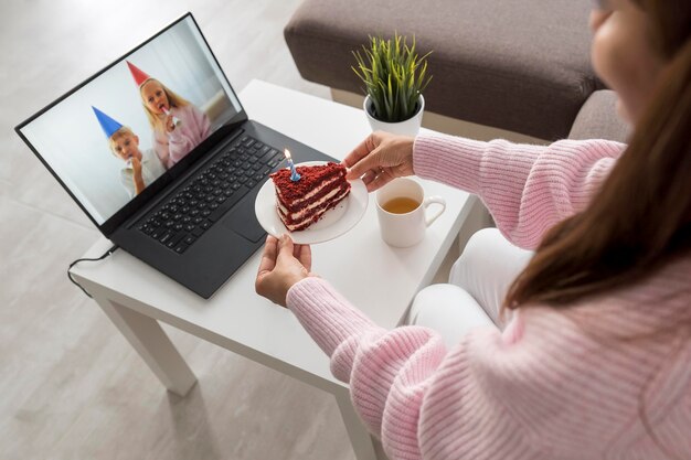 Mulher em casa em quarentena comendo bolo com um amigo no laptop
