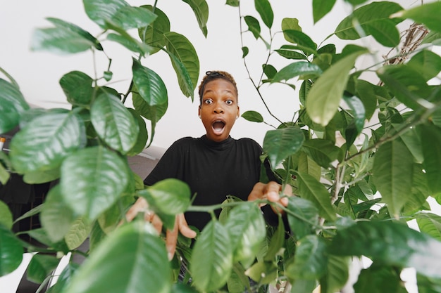 Mulher em casa. Rapariga com uma camisola preta. Mulher africana no escritório. Pessoa com vaso de flores.