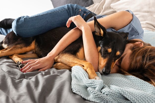 Mulher em cena completa abraçando um cachorro na cama
