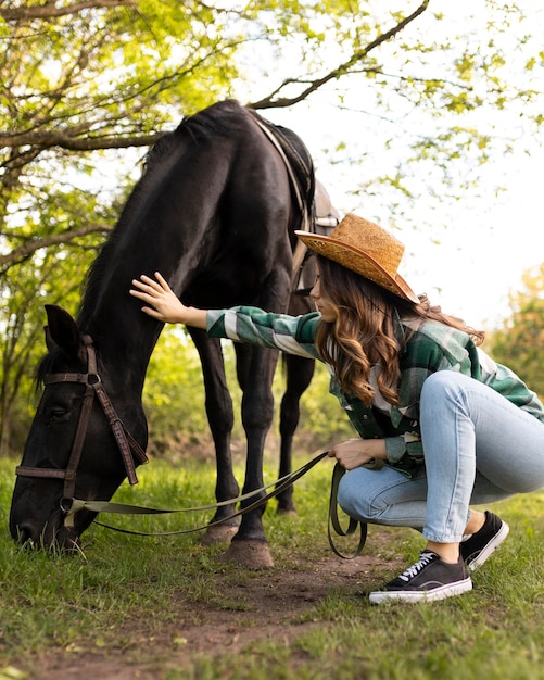 Mulher em cena completa acariciando o cavalo