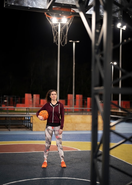 Foto grátis mulher em cena completa segurando uma bola de basquete ao ar livre