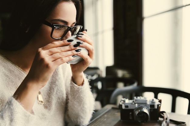 Foto grátis mulher em copos bebe café à mesa no café brilhante